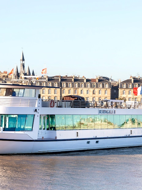 River cruise boat on the Garonne with Bordeaux cityscape in the background.