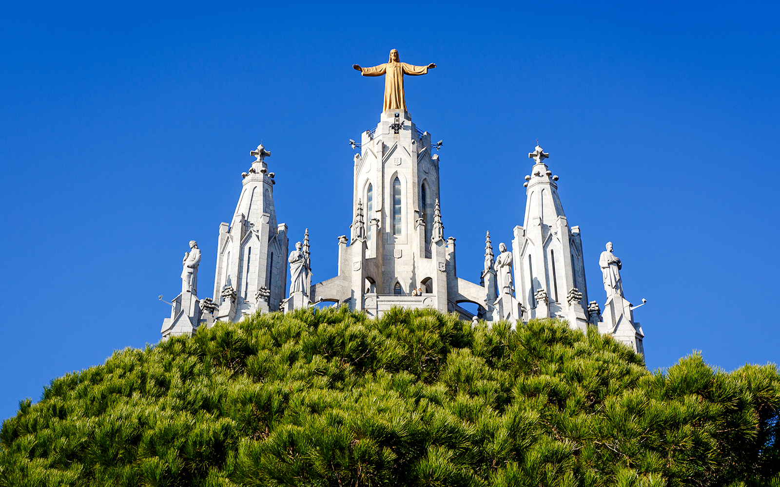 Temple of the Sacred Heart of Jesus, Barcelona, with statues and blue sky.