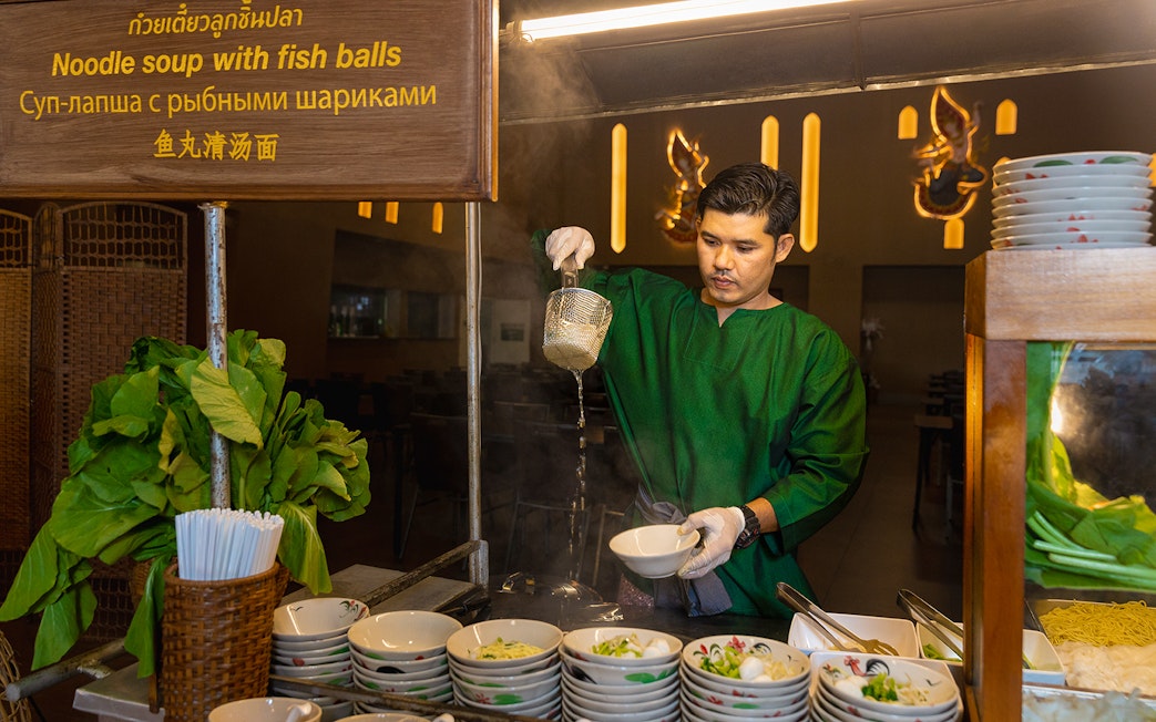 Vendor preparing noodle soup at Siam Niramit buffet.