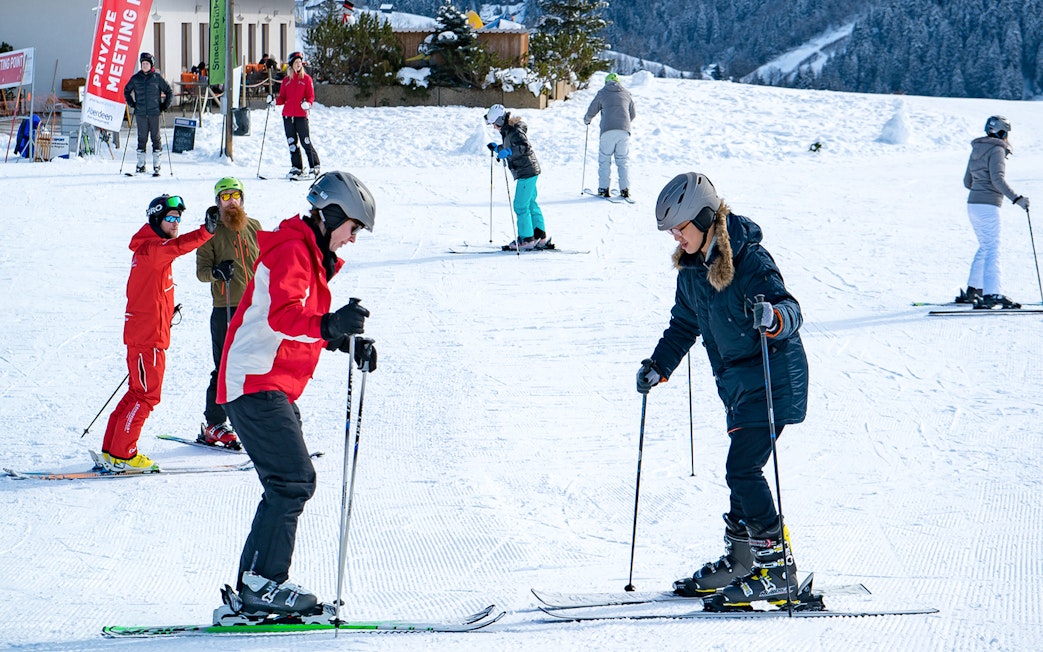 Beginner skiers learning on a snowy slope in Grindelwald during a full-day ski package from Interlaken.