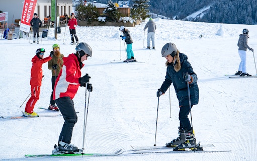 Beginner skiers learning on a snowy slope in Grindelwald during a full-day ski package from Interlaken.
