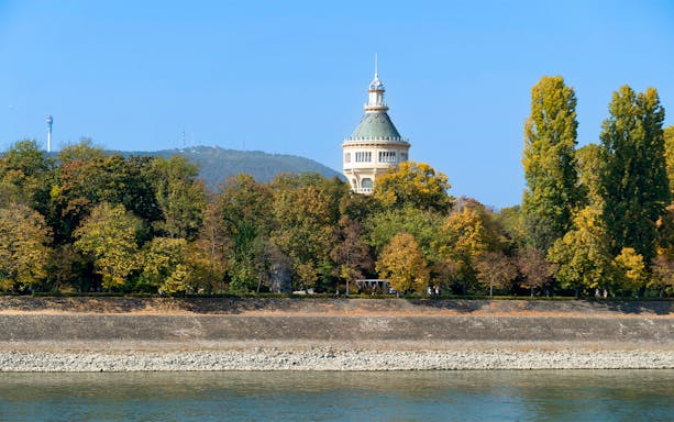 Margaret Island tower surrounded by trees, viewed from a cruise on the Danube in Budapest.