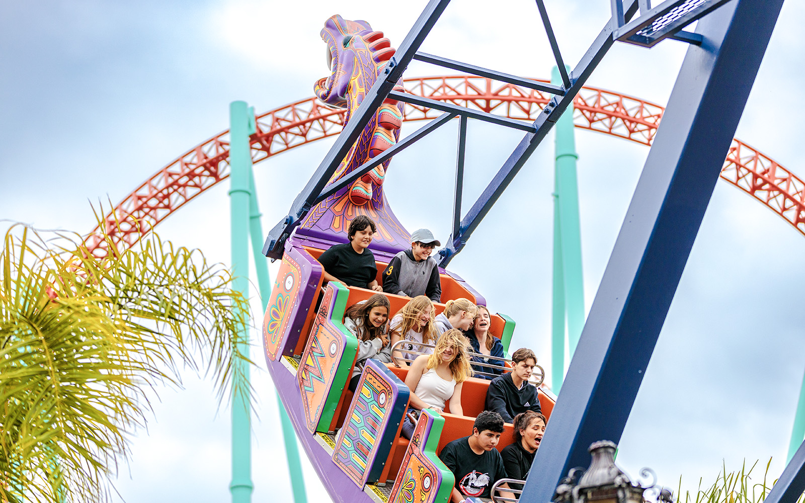 Riders enjoying the Dragon Swing at Knott's Berry Farm with roller coaster in background.