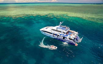 Catamaran on Outer Great Barrier Reef tour from Cairns with passengers enjoying the view.