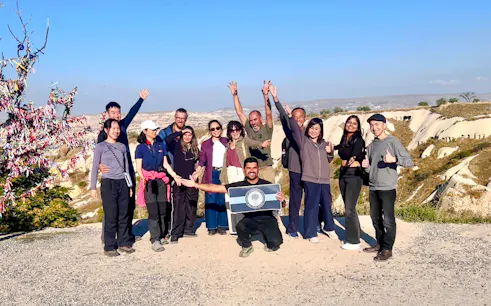 Group of tourists enjoying the Cappadocia Red Tour with scenic rock formations in the background.