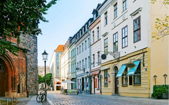 Cobblestone street with historic buildings in Berlin, part of the self-guided city exploration game.