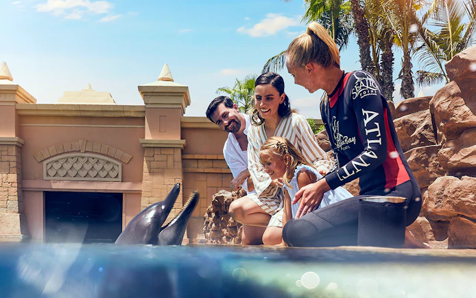 Family interacting with dolphins at Atlantis, The Palm, Dubai.