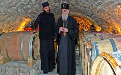 Monks in wine cellar at Tvrdos Monastery, Bosnia and Herzegovina, with wooden barrels.