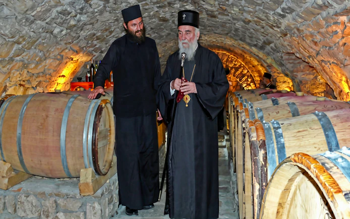 Monks in wine cellar at Tvrdos Monastery, Bosnia and Herzegovina, with wooden barrels.