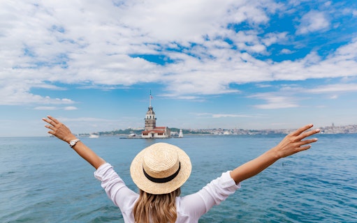 Person with arms raised facing Maiden's Tower on the Bosphorus, Istanbul.
