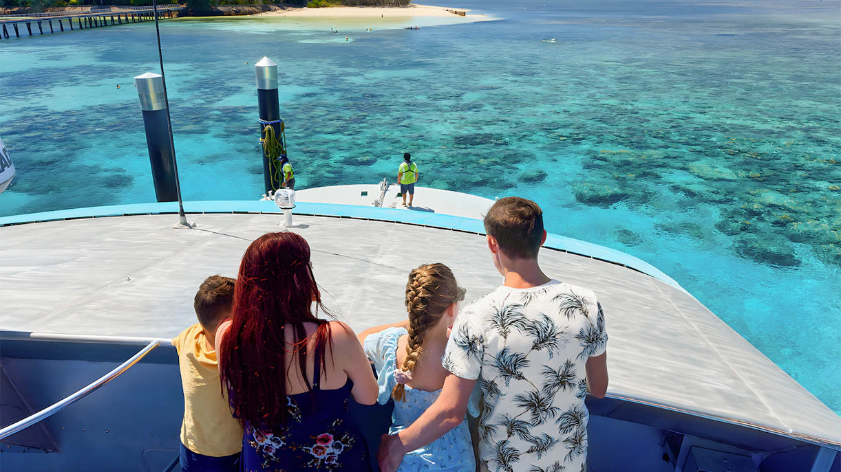Tourists on a boat approaching Green Island, clear waters visible, Cairns half-day cruise.
