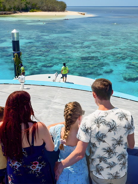 Tourists on a boat approaching Green Island, clear waters visible, Cairns half-day cruise.