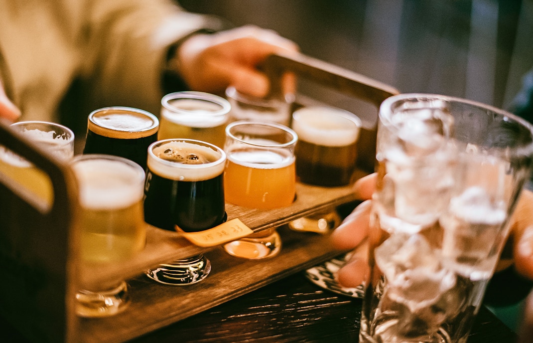 Flight of craft beers on a wooden tray during Busan pub crawl.
