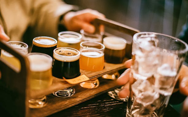 Flight of craft beers on a wooden tray during Busan pub crawl.