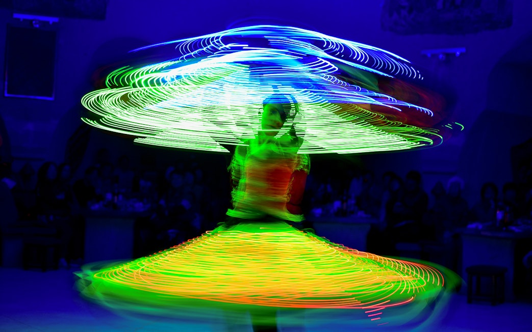 Tanoura dancer spinning with colorful lights on a cruise.