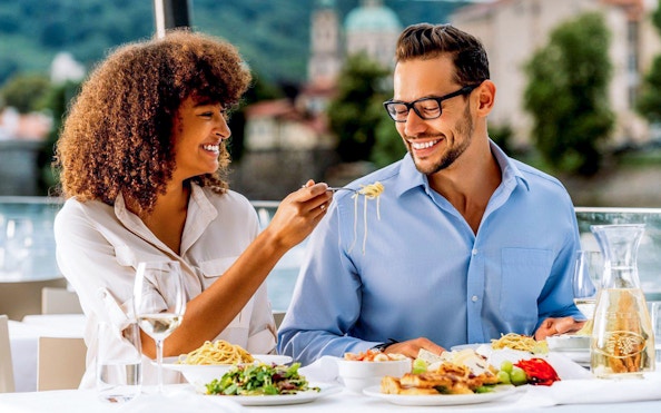 Couple enjoying lunch on Vltava River sightseeing cruise in Prague.