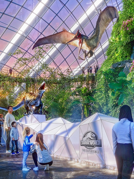 Visitors observing a pteranodon display at Jurassic World attraction.