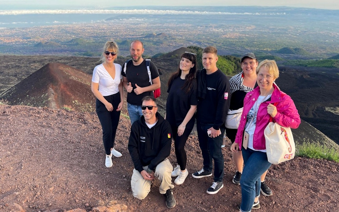 Tourists enjoying sunset views at Mount Etna summit.
