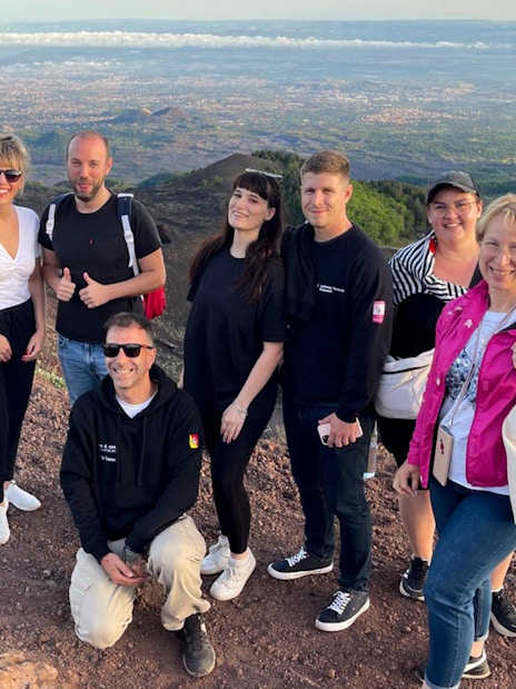 Tourists enjoying sunset views at Mount Etna summit.
