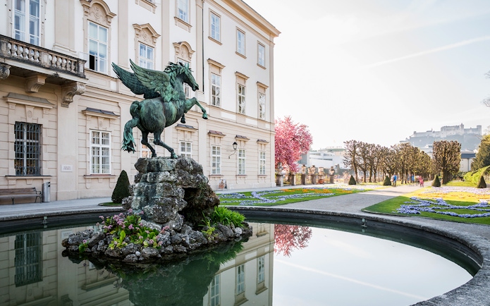 Pegasus statue in Mirabell Palace gardens, Salzburg, with Hohensalzburg Fortress in the background.