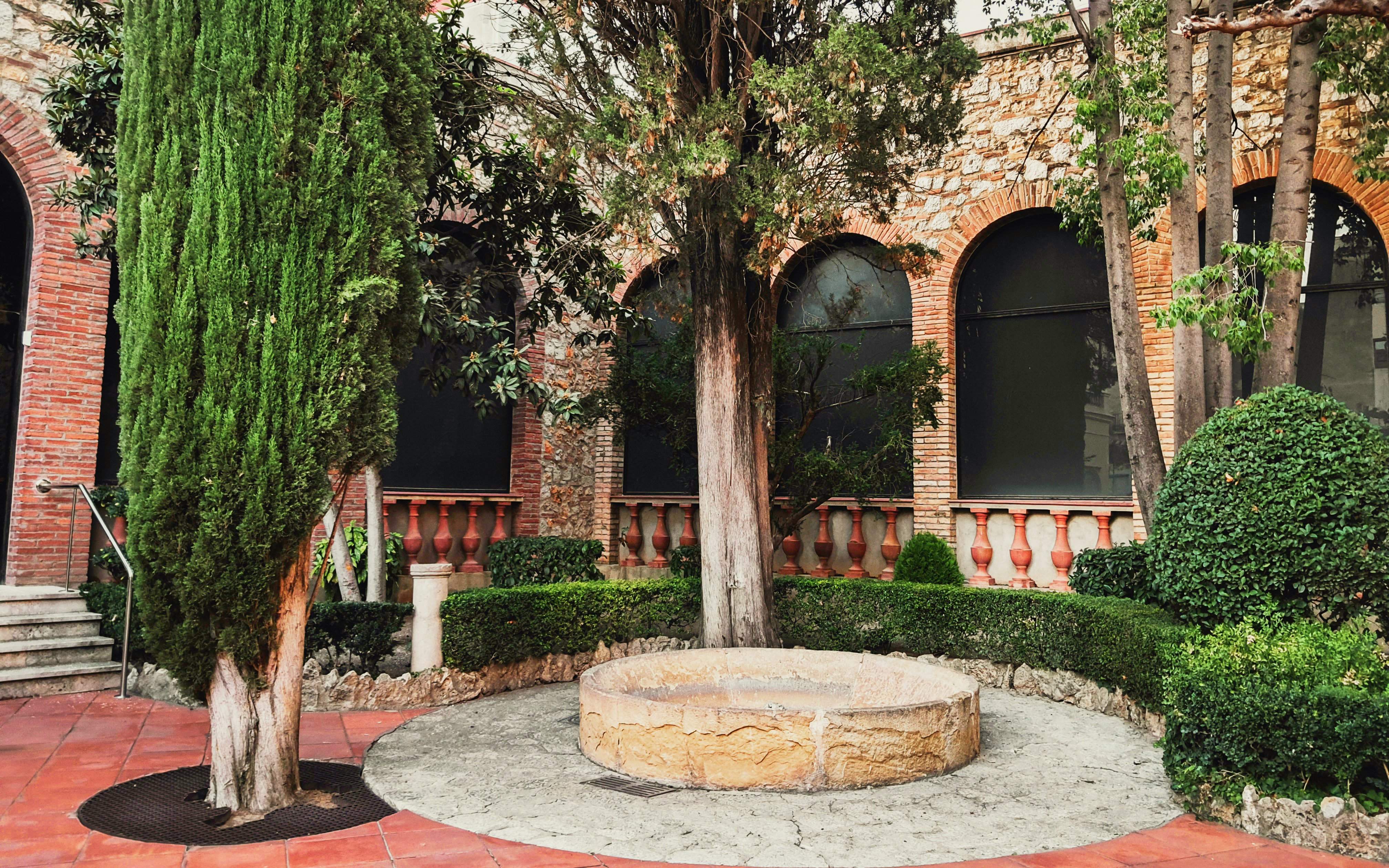 Garden area with trees and stone well at Dali Museum, Spain.