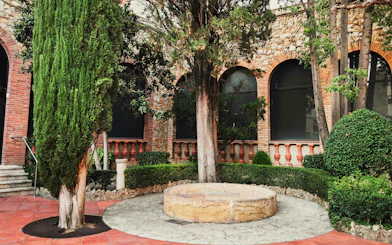Garden area with trees and stone well at Dali Museum, Spain.