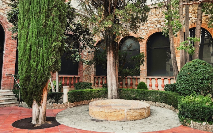 Garden area with trees and stone well at Dali Museum, Spain.