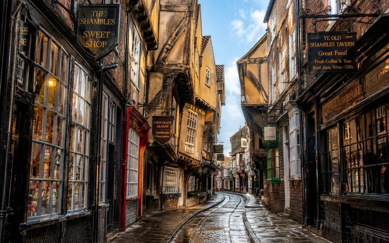 Narrow cobblestone street in York's Shambles with historic timber-framed buildings.