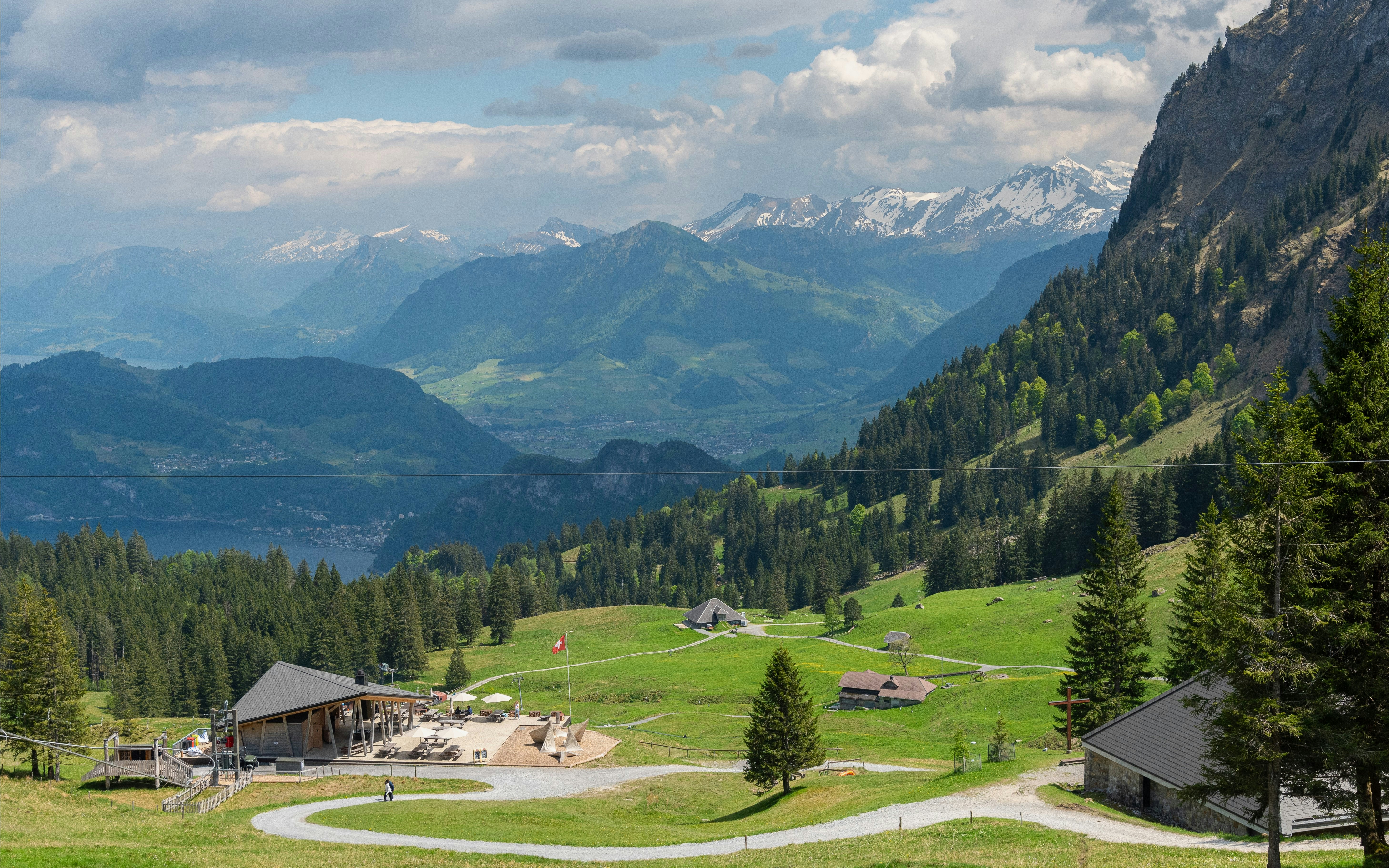 Mountain view from Fräkmüntegg, Mt Pilatus, with green meadows, trees, and distant peaks.
