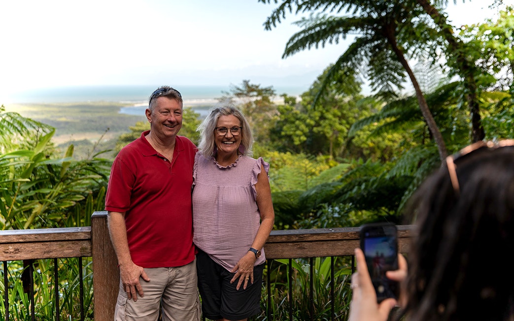 Couple posing on a guided Daintree Rainforest tour with lush greenery and ocean view.
