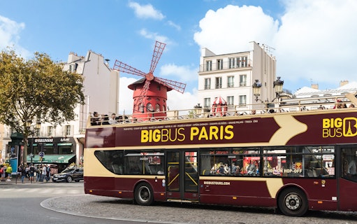 Open-top tour bus in front of the Moulin Rouge in Paris.