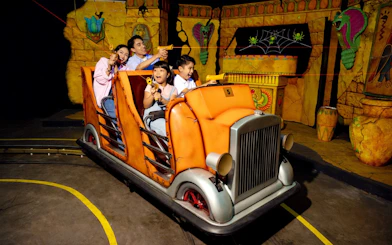 Family enjoying Laser Raiders ride at Legoland Malaysia, shooting targets in an ancient temple setting.