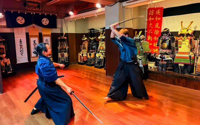 Samurai duel at Samurai Experience with traditional armors displayed in the background.