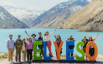 Group enjoying a tour at Embalse El Yeso, Chile, with mountains and lake in the background.