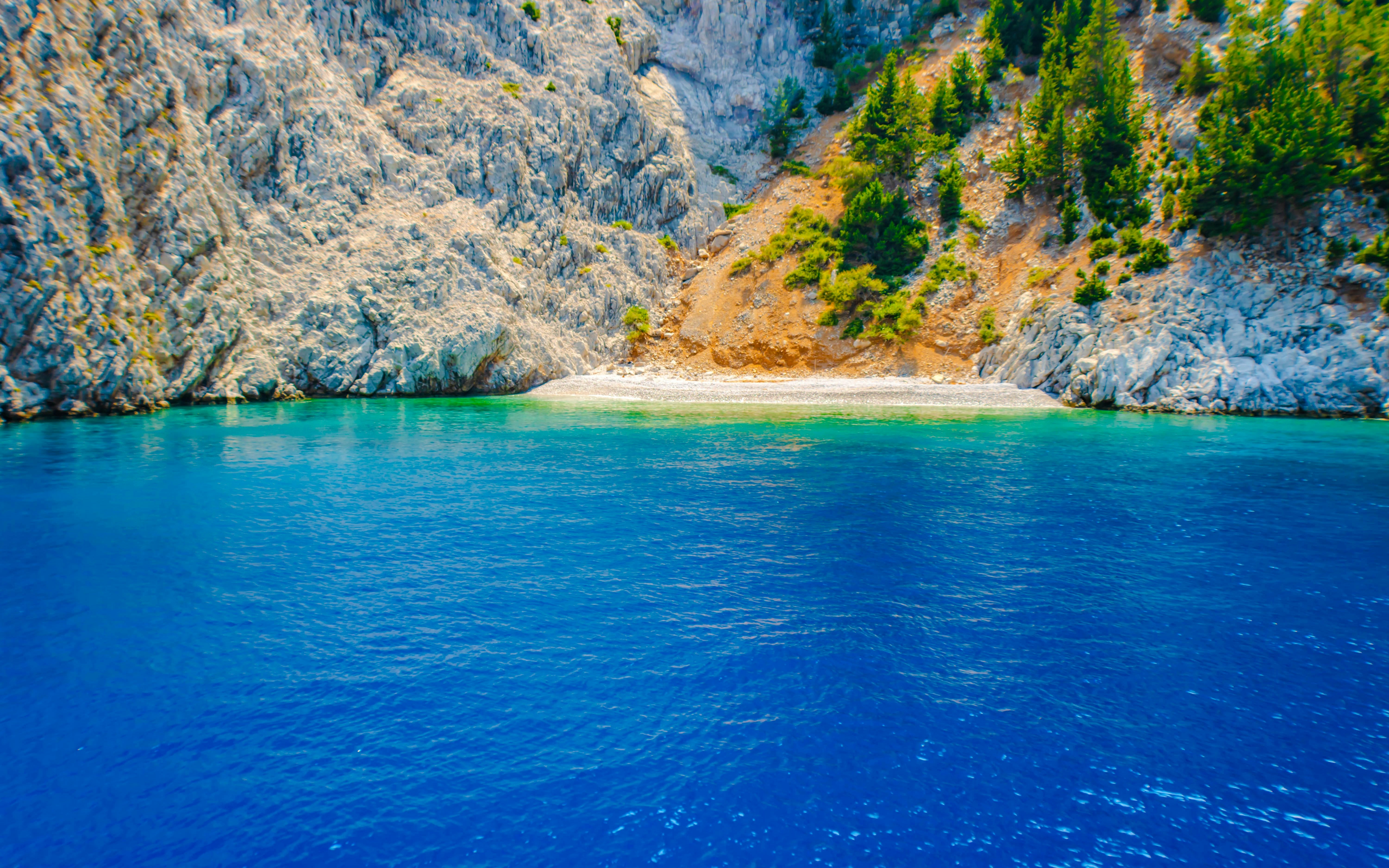 St George's Bay rocky shoreline and clear blue water during Rhodes cruise, Greece.