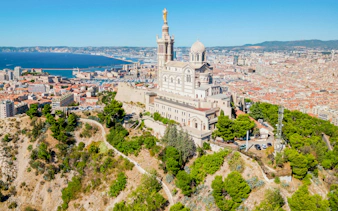 Notre Dame de la Garde overlooking Marseille cityscape and Mediterranean Sea.