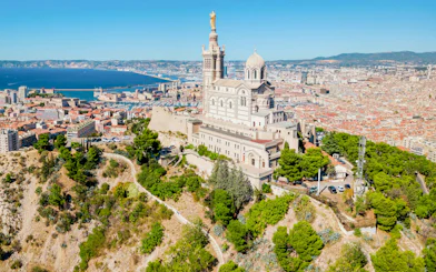 Notre Dame de la Garde overlooking Marseille cityscape and Mediterranean Sea.