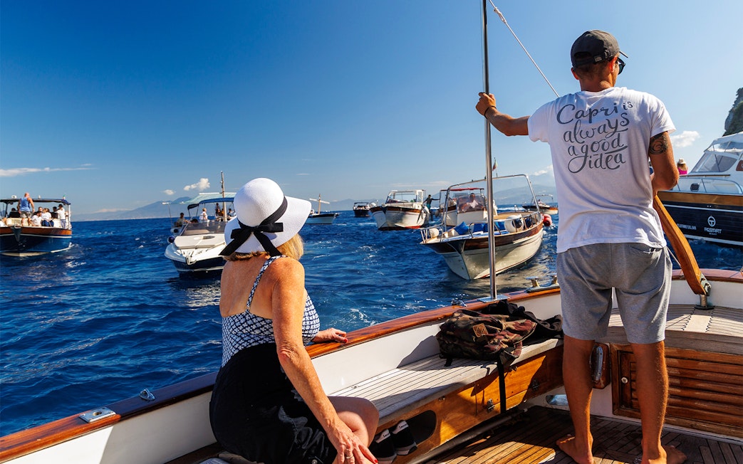 Couple enjoying boat tour near Capri with view of surrounding boats.