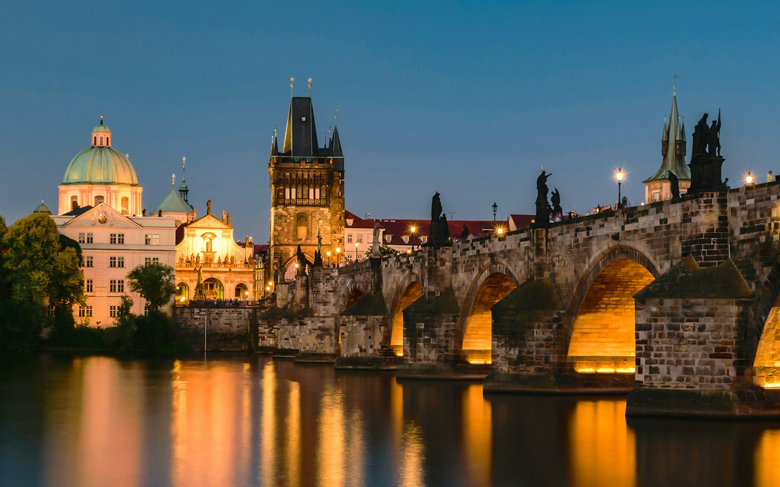 Charles Bridge and Prague skyline at dusk during sightseeing cruise.