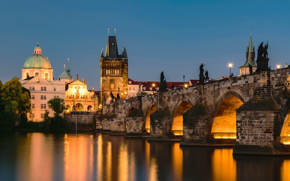 Charles Bridge and Prague skyline at dusk during sightseeing cruise.