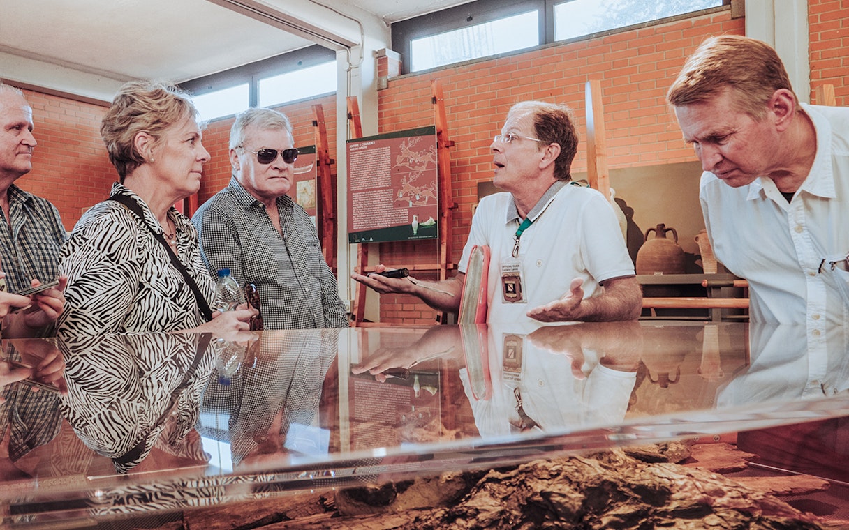 Tour guide discussing Herculaneum archives with visitors in a museum setting.