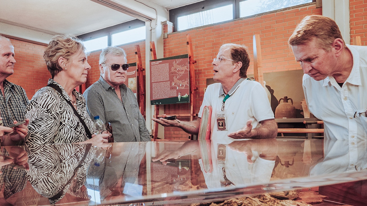 Tour guide discussing Herculaneum archives with visitors in a museum setting.
