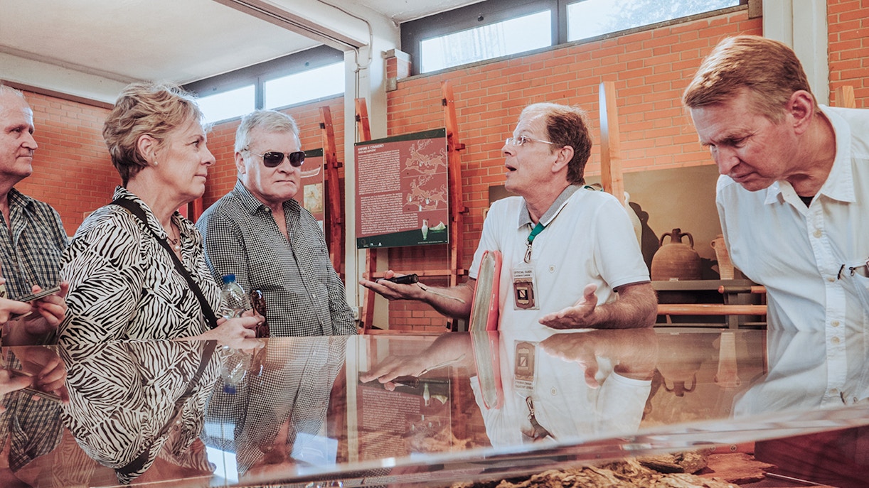Tour guide discussing Herculaneum archives with visitors in a museum setting.