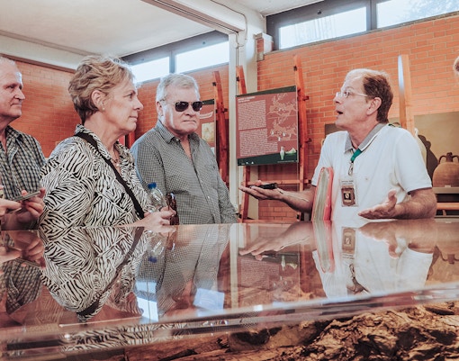Tour guide discussing Herculaneum archives with visitors in a museum setting.