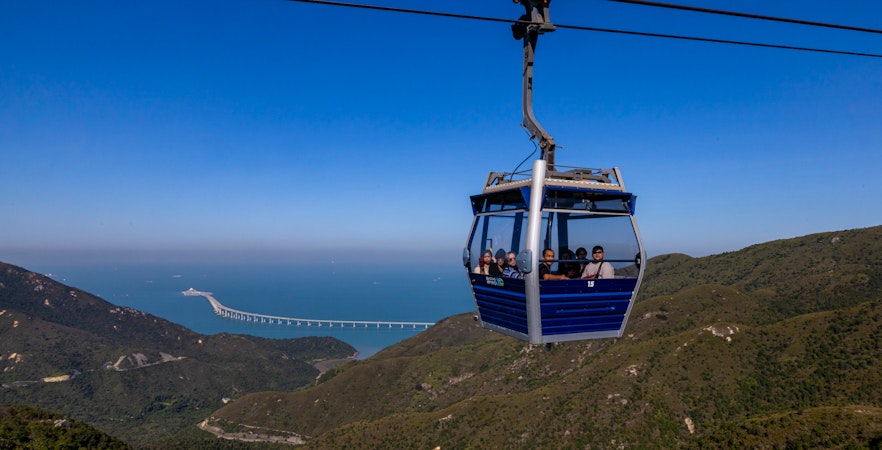 Ngong Ping cable car gliding over lush green hills in Hong Kong.