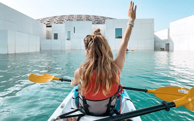 Kayaker paddling near Louvre Abu Dhabi's dome on a guided tour.