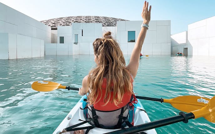 Kayaker paddling near Louvre Abu Dhabi's dome on a guided tour.