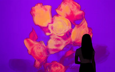 Silhouette of a person viewing vibrant floral digital art at Eternal Nature, Arte Museum, New York.