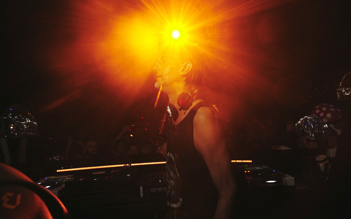 DJ performing at Club Chinois with vibrant lighting effects.