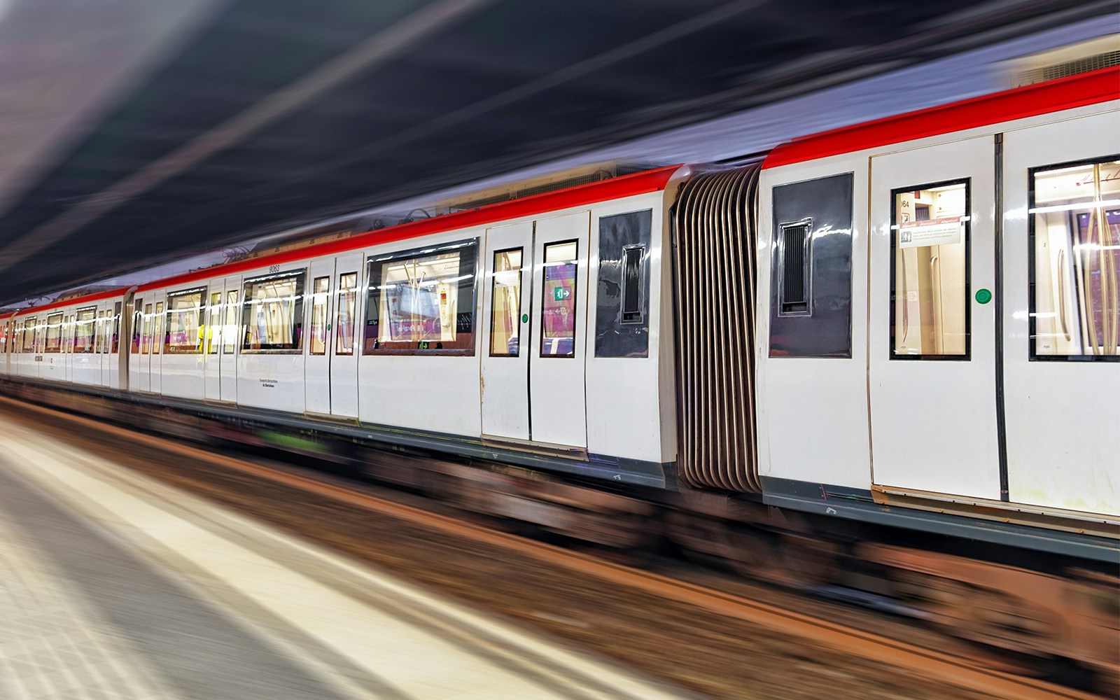 Barcelona metro train arriving at a station platform with passengers boarding.